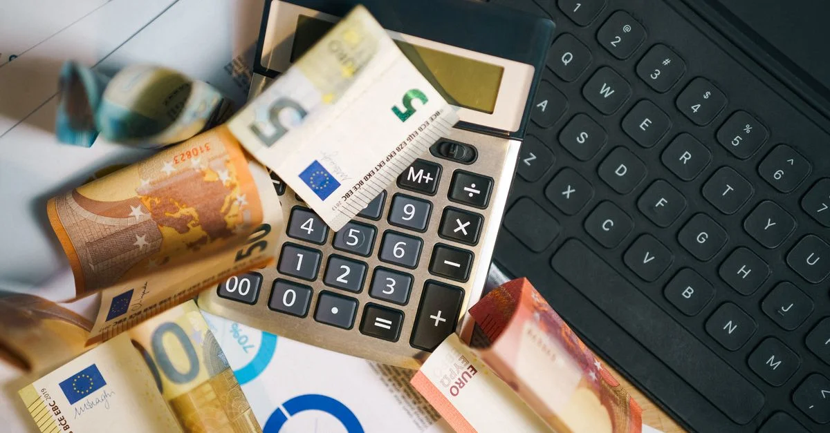 Une configuration financière avec des billets en euro, une calculatrice et un clavier d'ordinateur portable pour l'analyse commerciale.