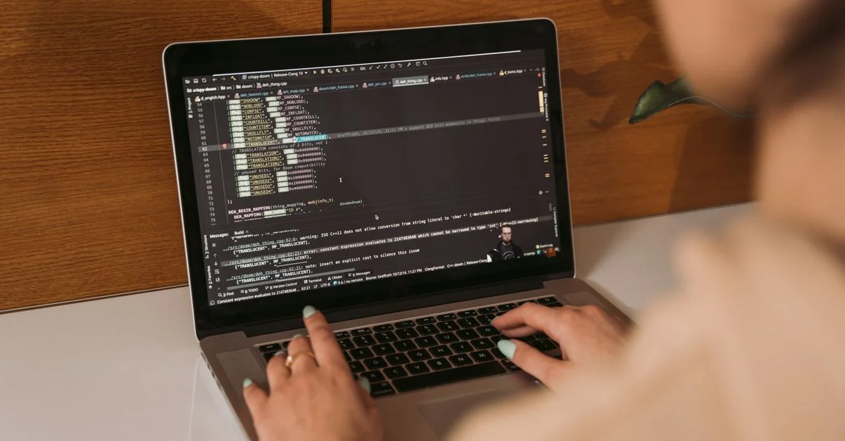 Gros plan d'une femme codant avec un ordinateur portable dans un environnement de bureau, mettant en avant la technologie moderne.