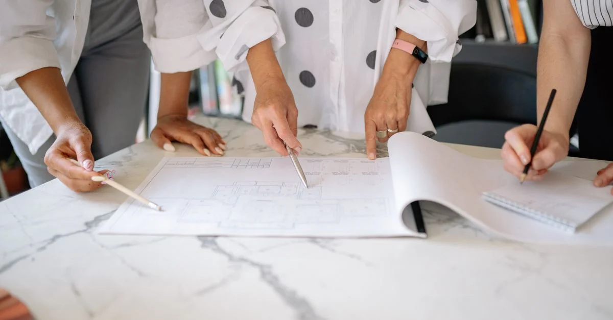 Équipe collaborant sur des plans architecturaux, mettant en avant le travail d'équipe et la planification dans un cadre de bureau.