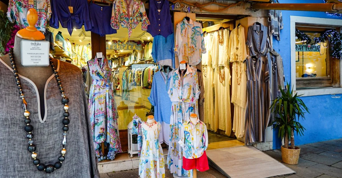 Découvrez une boutique italienne colorée avec des robes élégantes et des tissus vibrants en exposition.